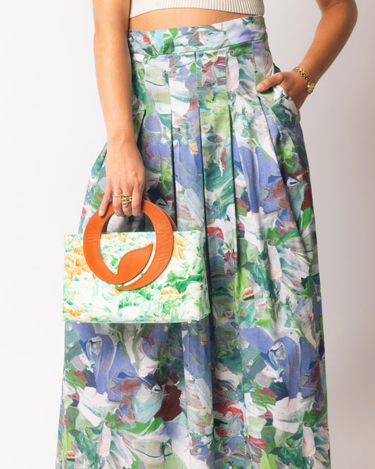 Person wearing a floral skirt and holding a matching floral handbag against a white background