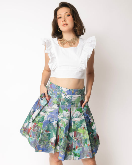 Woman wearing a white ruffled top and floral skirt against a white background