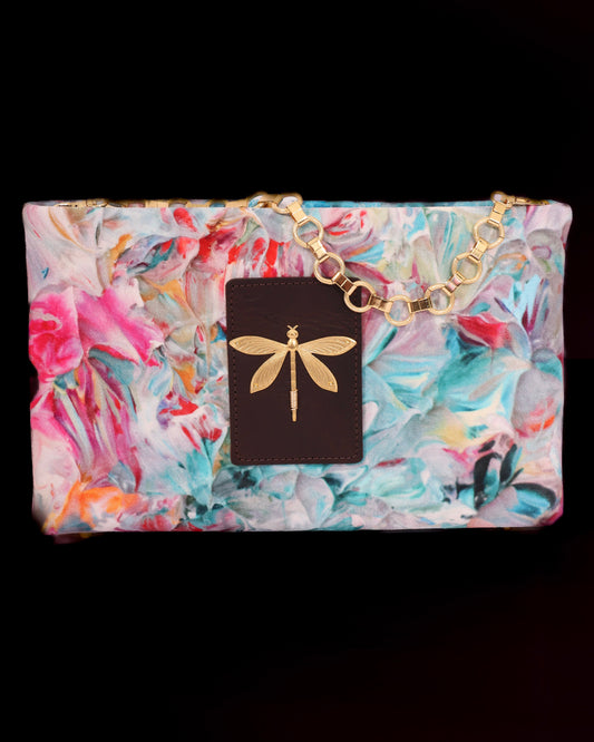 Floral-patterned clutch bag with a brass chain and brass dragonfly accent
