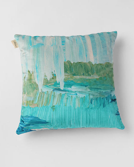 A square-shaped throw pillow with a hand-painted design in shades of blue and green, depicting a serene landscape.
